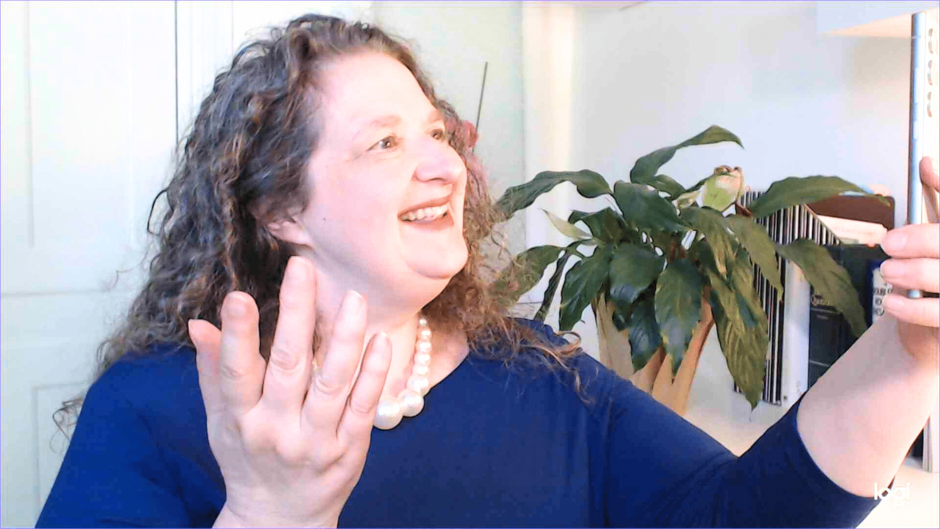 Andrea Stenberg, curly haired woman dressed in blue recording herself speaking to her smartphone camera